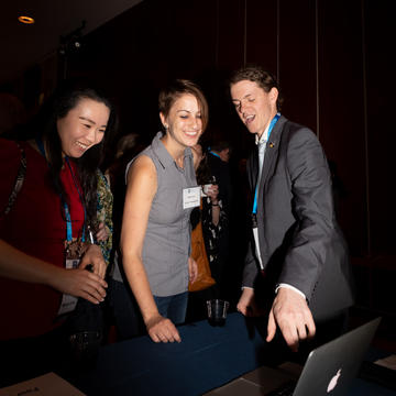 Three students looking and pointing at a camera 